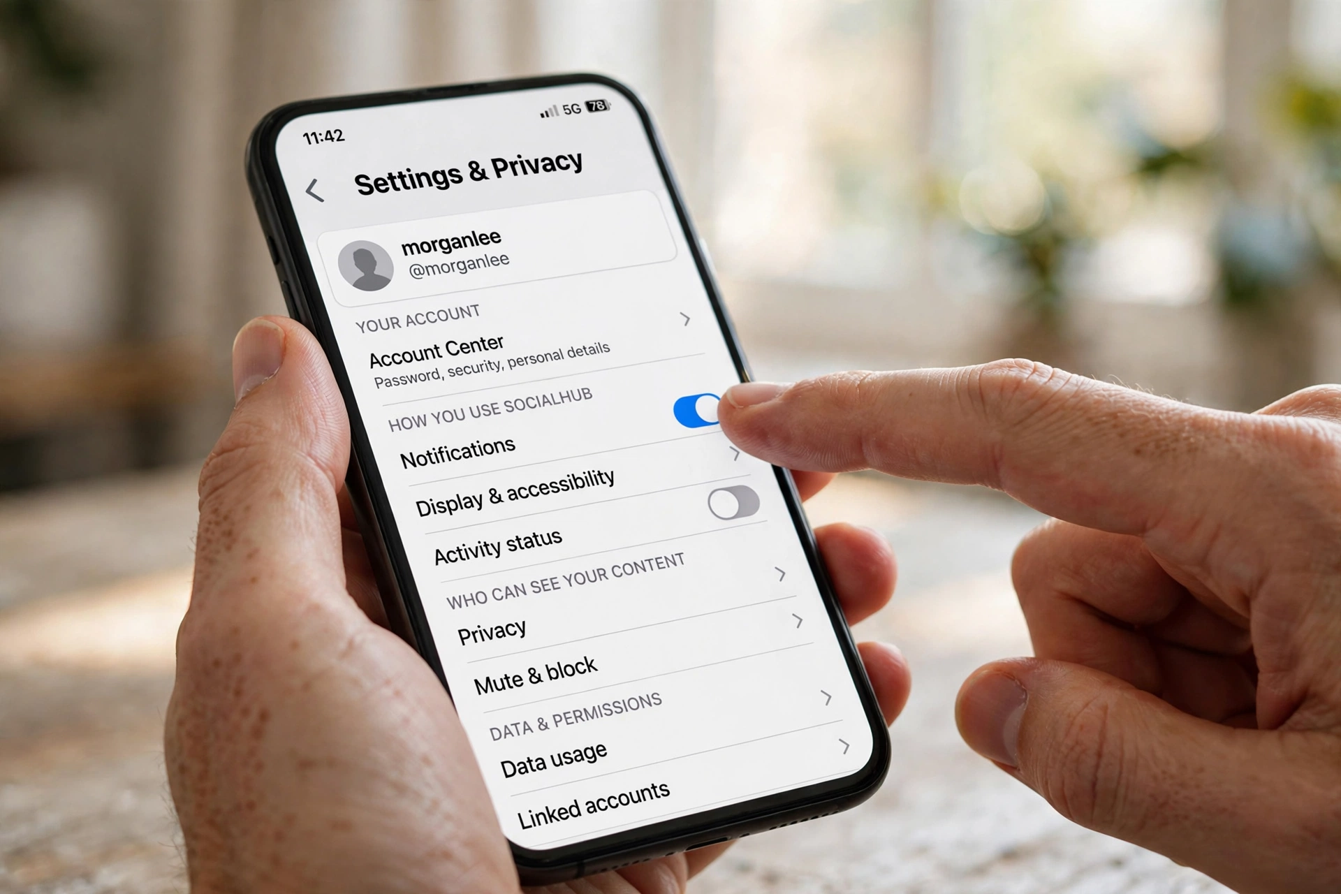 Close up of a hand holding a smartphone showing a social media app settings menu on screen